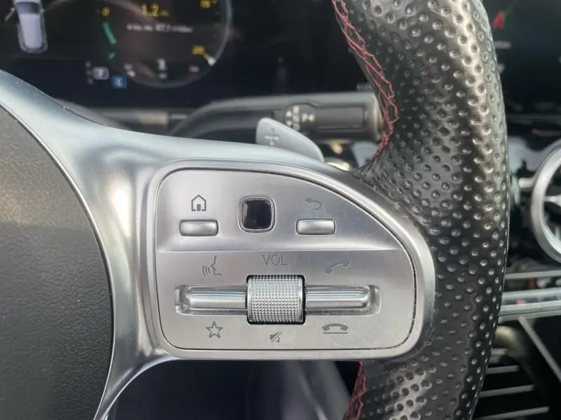 Gros plan sur les commandes du volant perforé avec surpiqûres rouges du Mercedes GLA 200 D AMG-LINE 2022.