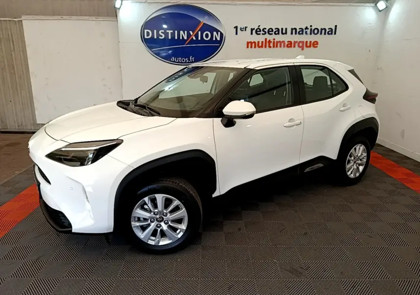 Toyota Yaris Cross blanc vue 3/4 avant droit en intérieur, avec jantes alliage et protections noires contrastées.