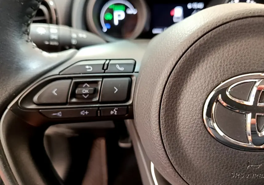 Gros plan sur le volant cuir noir de la Toyota Yaris Cross 2022 avec commandes multifonctions et logo Toyota central.