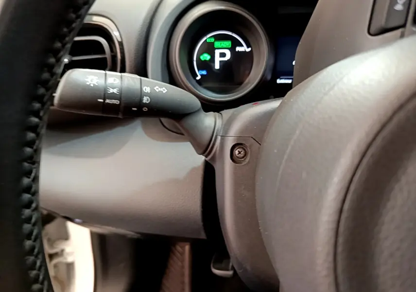 Gros plan sur le combiné d'instruments et le commodo gauche du volant cuir de la Toyota Yaris Cross blanche 2022.