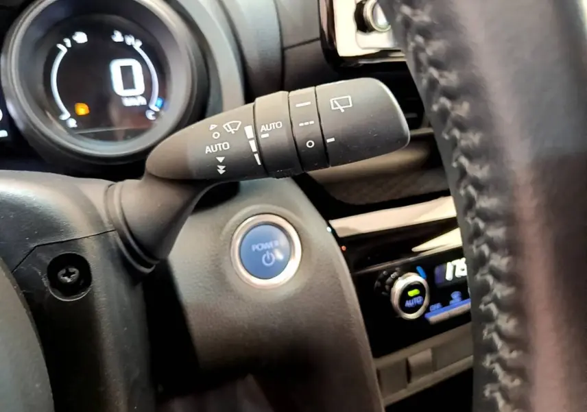 Gros plan sur la commande d'essuie-glace et le bouton Power dans l'habitacle noir de la Toyota Yaris Cross blanche.