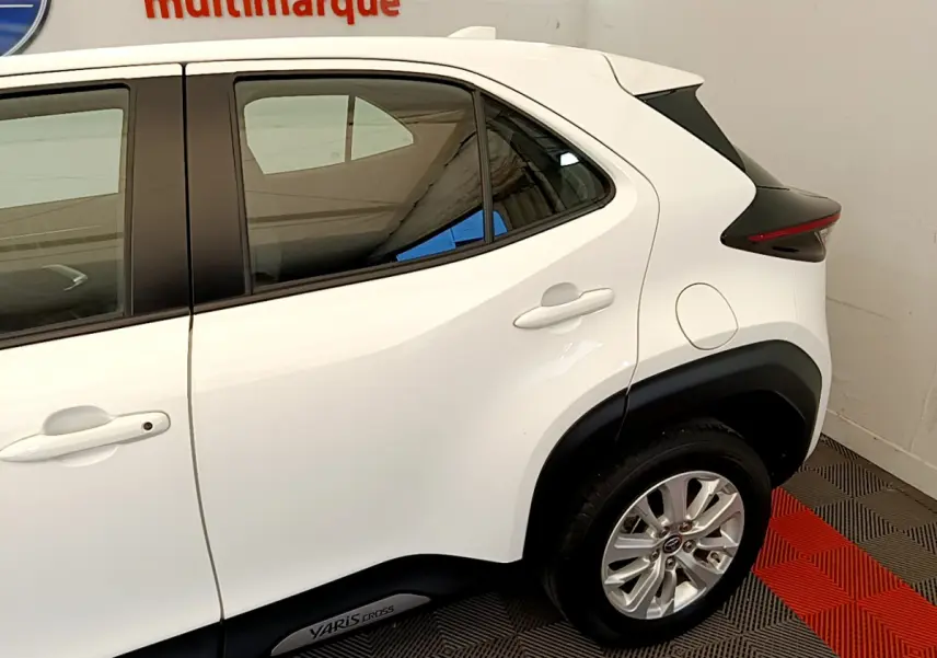 Vue côté droit arrière du Toyota Yaris Cross blanc avec jantes alliage et logo Yaris Cross sur bas de caisse.