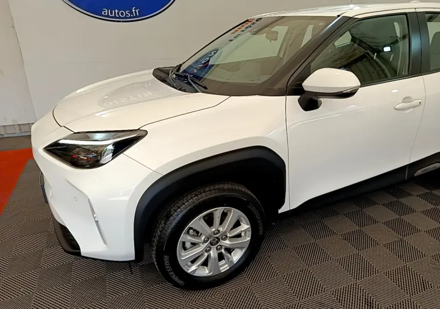 Vue 3/4 avant droit d'une Toyota Yaris Cross blanche avec protections noires autour des passages de roues.