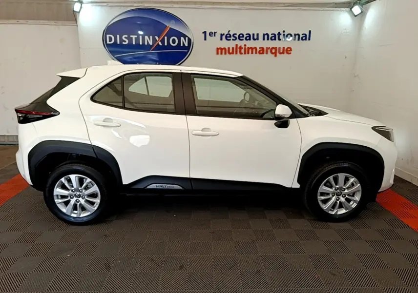 Profil côté gauche d'un Toyota Yaris Cross blanc 2022 avec jantes alliage et protections noires sur les passages de roues.