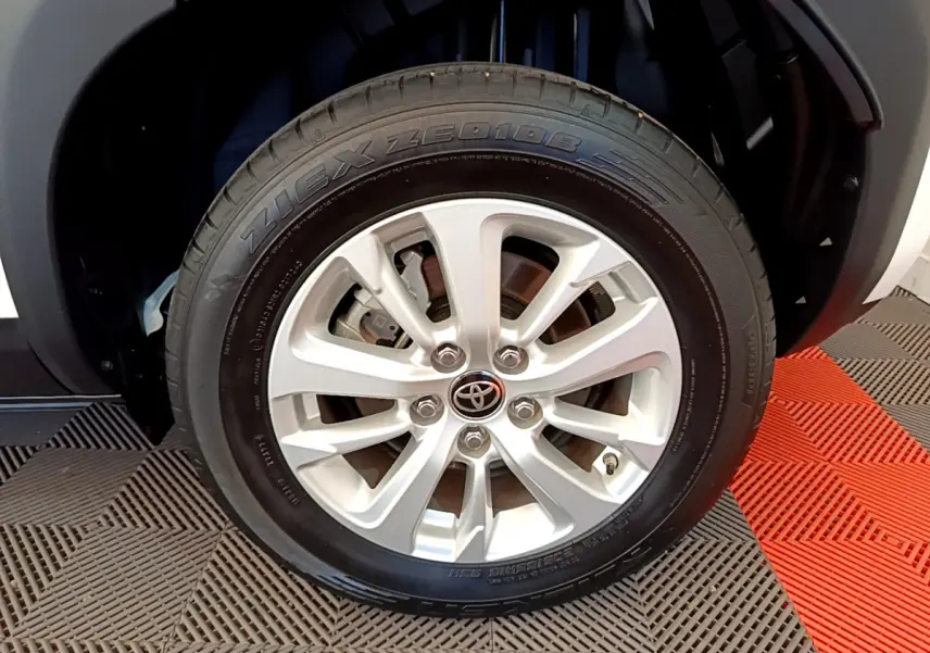 Gros plan sur la roue avant droite du Toyota Yaris Cross blanc, mettant en valeur la jante alliage et le logo Toyota central.