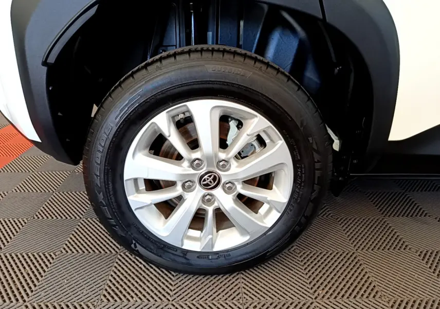 Gros plan sur la roue avant droite blanche d'un Toyota Yaris Cross 1.5 Hybrid 116h avec jante argentée et logo Toyota central.