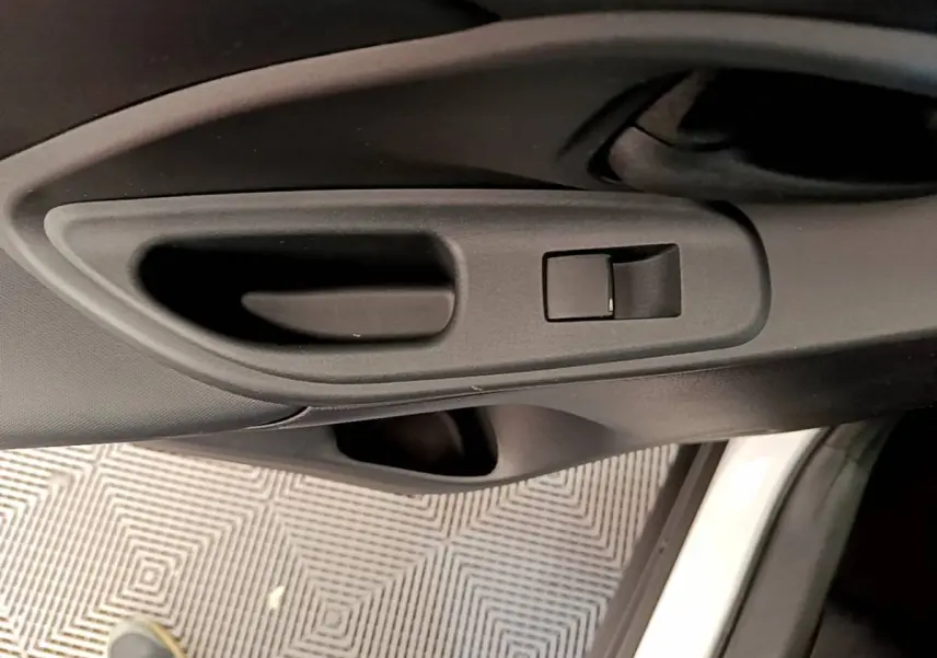 Poignée intérieure noire de la porte côté conducteur d'une Toyota Yaris Cross blanche, vue en gros plan.