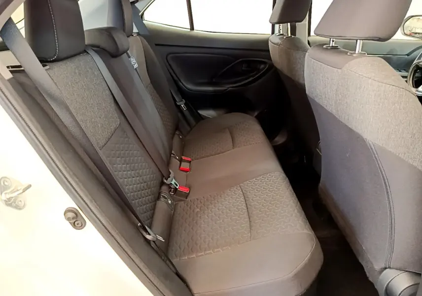 Vue côté gauche de la banquette arrière grise du Toyota Yaris Cross blanc, avec ceintures et appuie-têtes visibles.