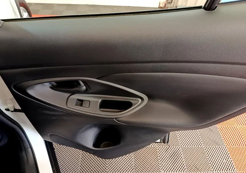 Gros plan sur la porte côté gauche intérieure noire du Toyota Yaris Cross blanc, avec poignée et commande de fenêtre.