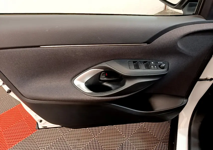 Intérieur côté gauche de la porte avant blanche de la Toyota Yaris Cross 2022 avec commandes de vitres et poignée noire.