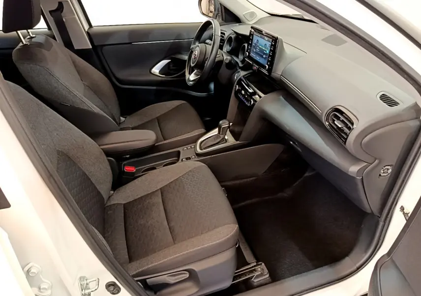 Intérieur avant droit de la Toyota Yaris Cross blanche 2022, avec sièges tissu gris et écran tactile central visible.