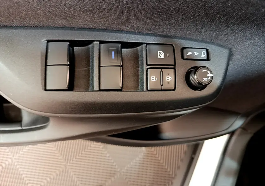 Gros plan sur les commandes de porte côté conducteur de la Toyota Yaris Cross 2022, boutons noirs sur panneau gris.