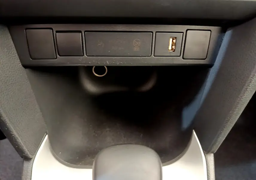 Gros plan sur la console centrale noire de la Toyota Yaris Cross 1.5 Hybrid avec port USB visible.