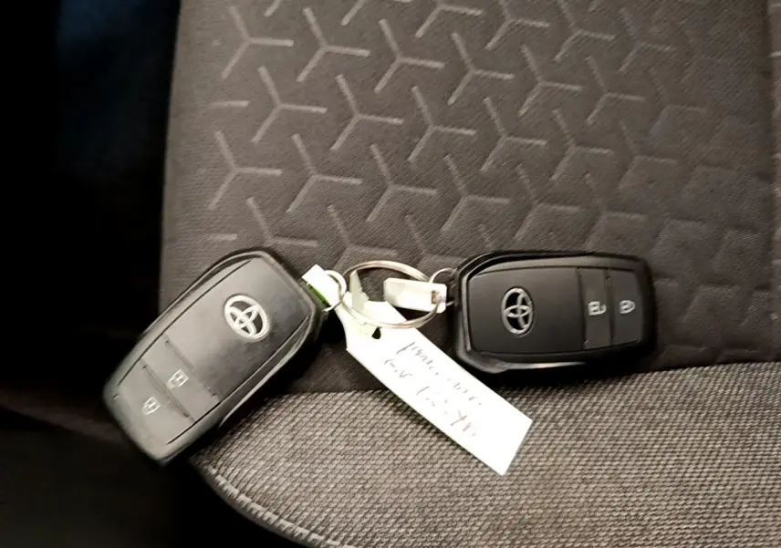 Gros plan sur deux clés Toyota noires posées sur un siège tissu gris à motifs géométriques.