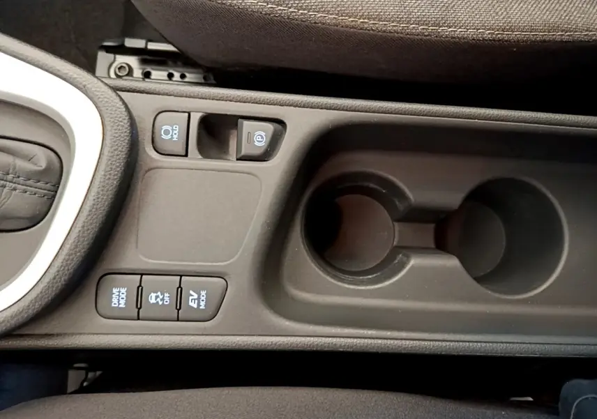 Vue rapprochée de la console centrale noire de la Toyota Yaris Cross 2022 avec boutons de modes de conduite et porte-gobelets.