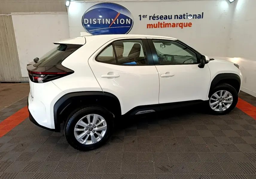 Profil côté gauche d'une Toyota Yaris Cross blanche 2022 en version hybride, dans un showroom lumineux.
