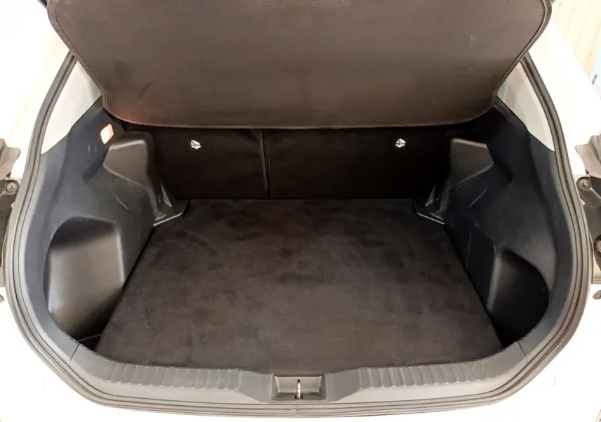 Coffre ouvert vu de face du Toyota Yaris Cross blanc, montrant un espace de chargement propre et spacieux.