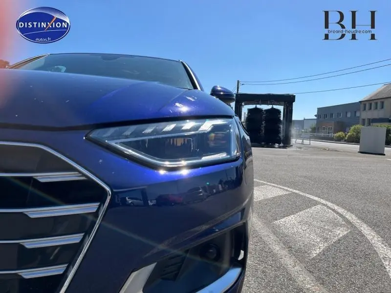 Gros plan sur l'avant droit bleu métallisé de l'Audi A4 Avant 30 TDI avec phares LED et calandre distinctive.