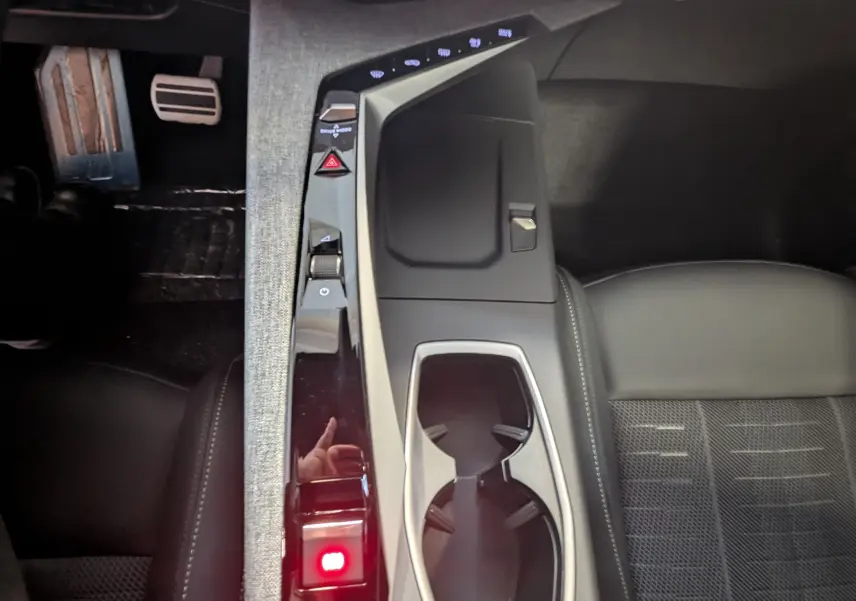 Vue plongeante sur la console centrale et le pédalier alu du Peugeot 3008 Hybrid gris titane, intérieur tissu noir.