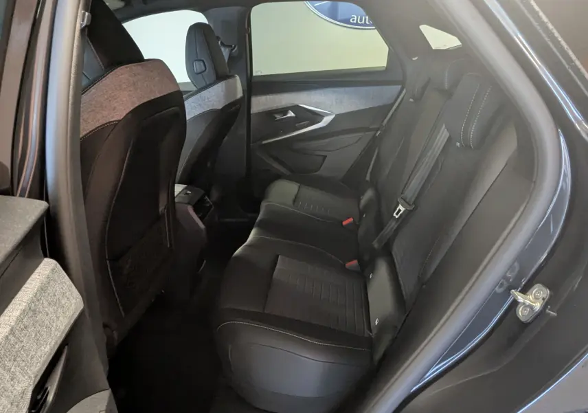Vue intérieure arrière droite sur les sièges en tissu et cuir gris du Peugeot 3008 Hybrid 145 GT 2025 avec surpiqûres blanches.