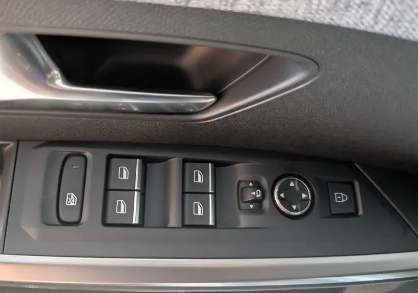 Gros plan sur les commandes de lève-vitres et réglage des rétroviseurs côté conducteur du Peugeot 3008 gris titane.