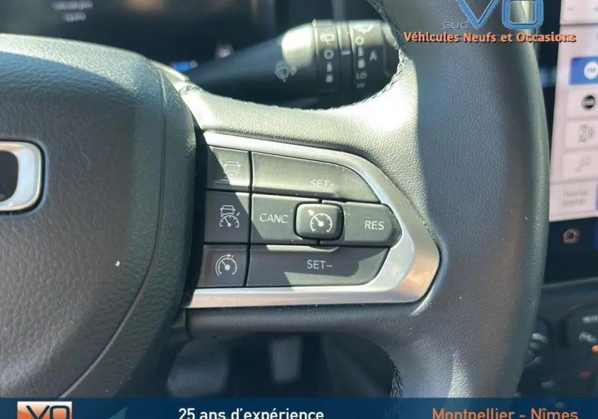 Gros plan sur les commandes du régulateur de vitesse au volant noir du Jeep Renegade 2024 e-Hybrid Summit.
