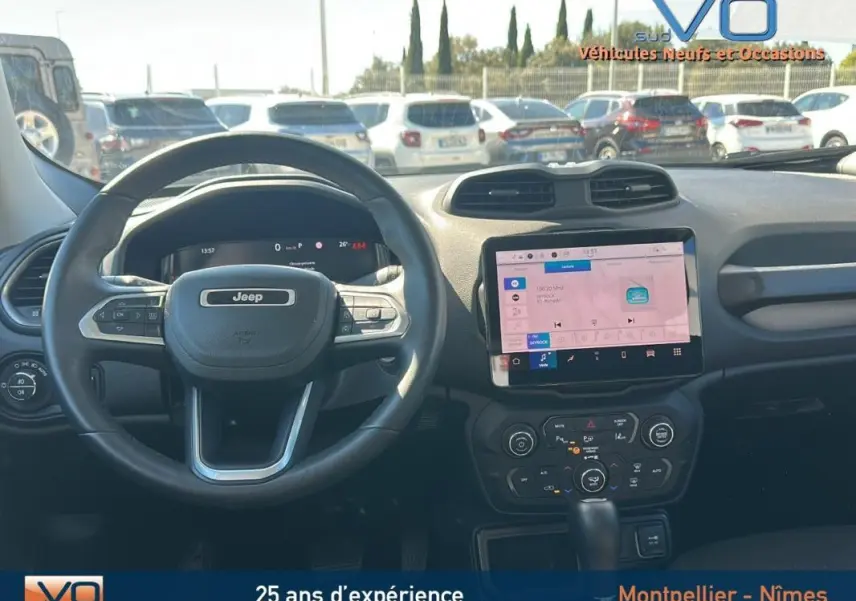 Vue intérieure centrée sur le volant Jeep noir et l'écran tactile du tableau de bord du Renegade 2024.