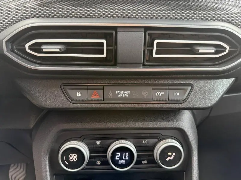 Vue rapprochée du tableau de bord gris du Dacia Jogger 2025, avec commandes climatisation et aérateurs rectangulaires.