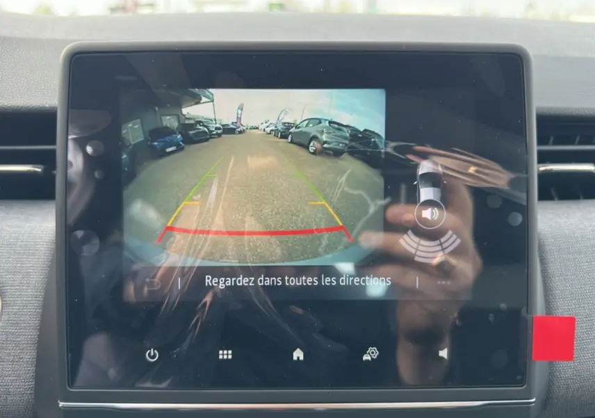 Écran tactile intérieur montrant la caméra de recul d'une Renault Clio gris rafale, avec vue arrière du parking.