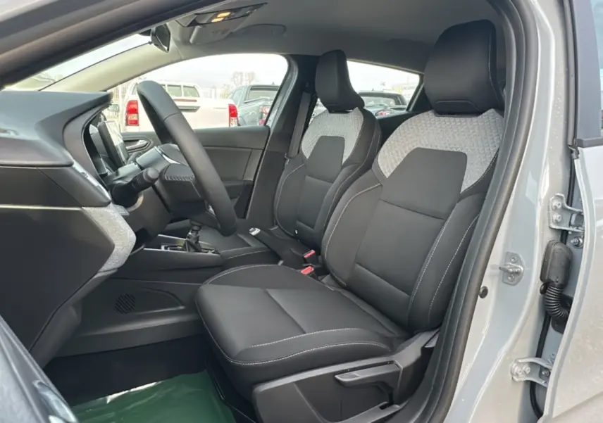 Vue intérieure côté conducteur de la Renault Clio gris rafale 2025, sièges avant en tissu noir avec inserts gris.