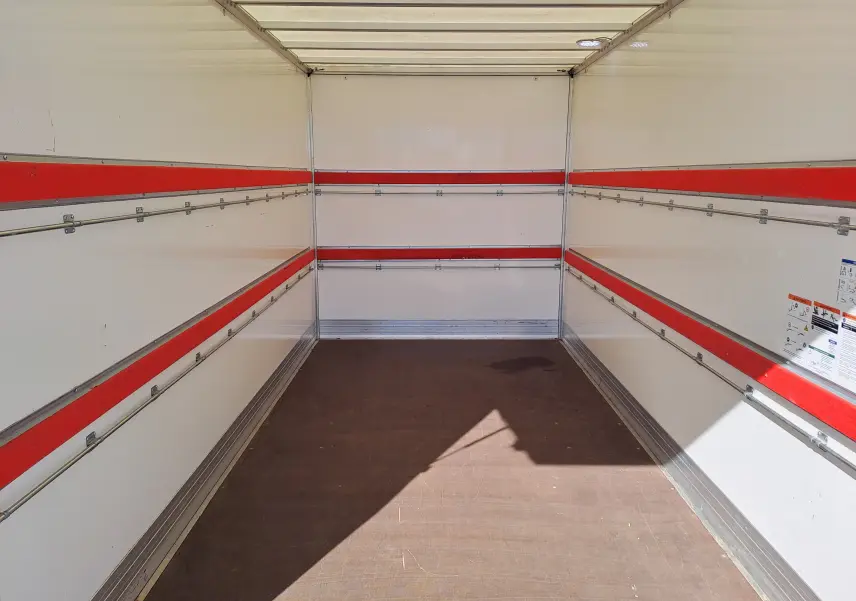 Intérieur vide du coffre blanc du Nissan Interstar Châssis Cabine L3H1, vue de l'arrière vers l'avant avec bandes rouges latérales.