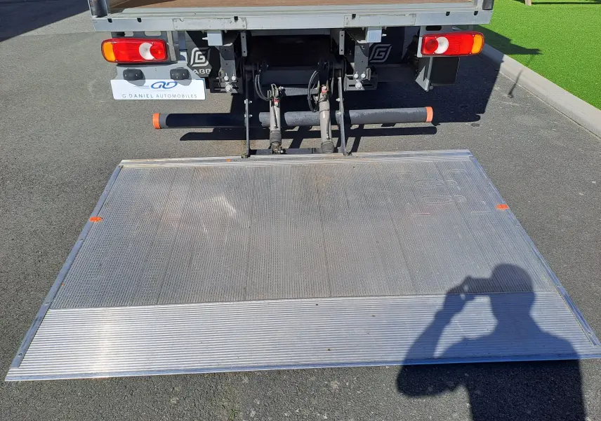 Vue arrière d’un Nissan Interstar blanc 2024 avec hayon élévateur déployé sur sol asphalté.