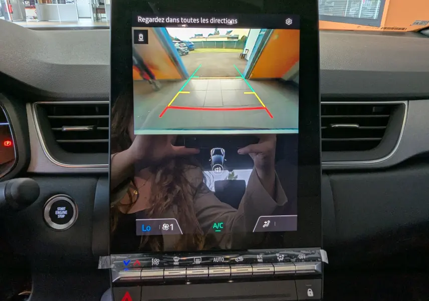 Écran central du Renault Captur 2025 affichant la caméra de recul avec lignes de guidage colorées, intérieur noir.