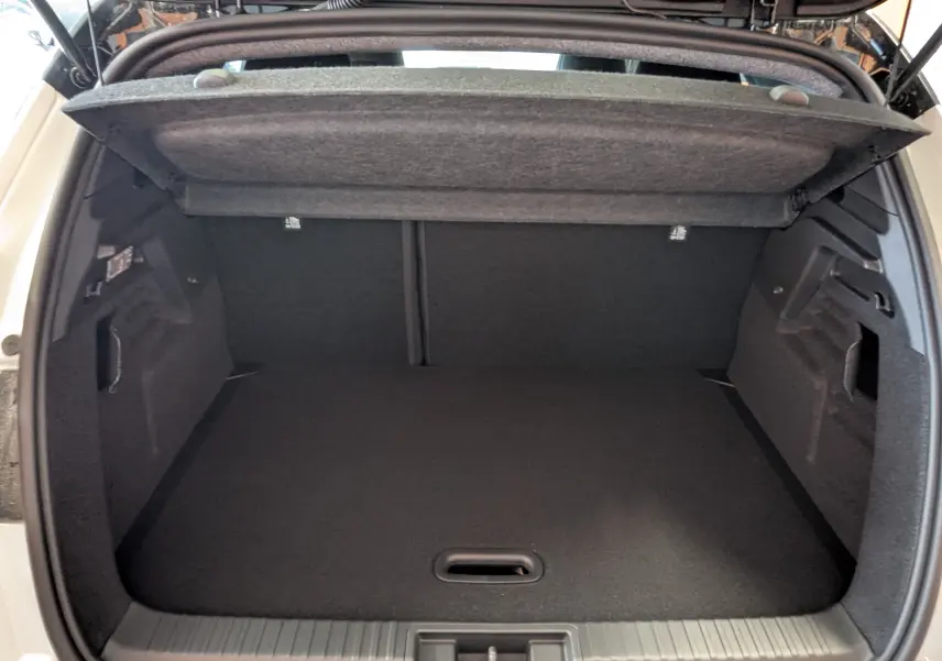 Coffre ouvert du Renault Captur E-Tech blanc nacré avec toit noir, vue arrière montrant l'espace de chargement vide.