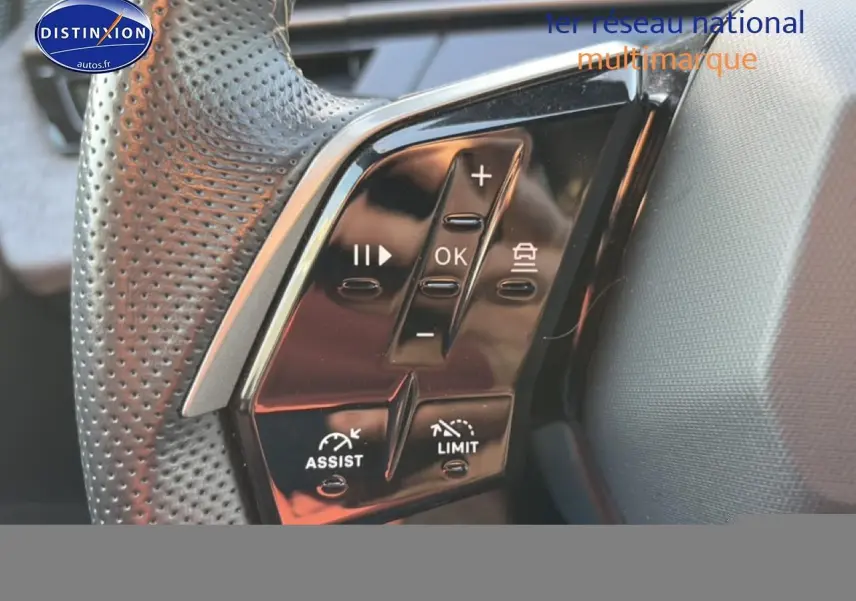 Gros plan sur les commandes multifonctions noires du volant cuir perforé côté gauche du Peugeot 3008 gris 2025.