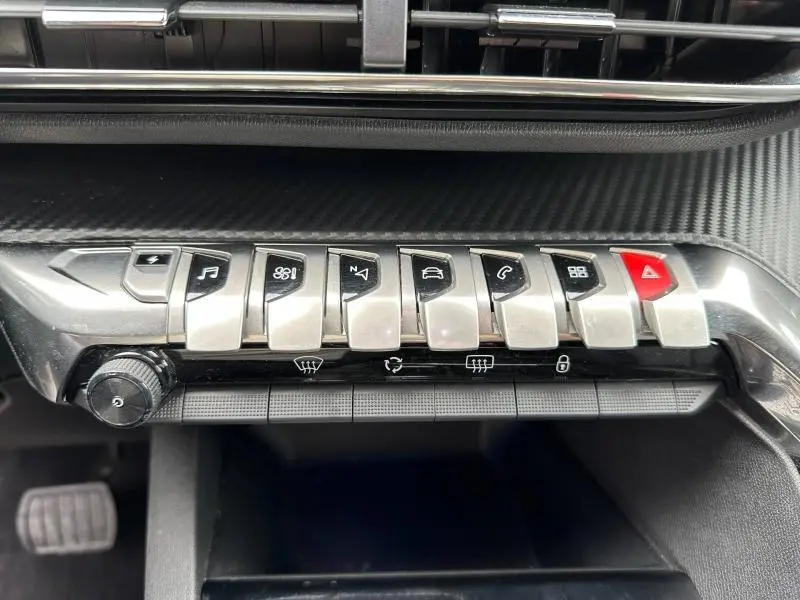 Gros plan sur les commandes centrales argentées du tableau de bord du Peugeot 3008 Hybride Rechargeable noir, avec touches fonctionnelles distinctives.