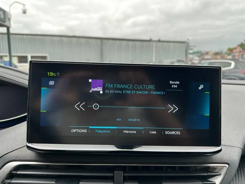 Écran tactile central du tableau de bord du Peugeot 3008 noir Perla Nera, affichant une radio FM en extérieur.