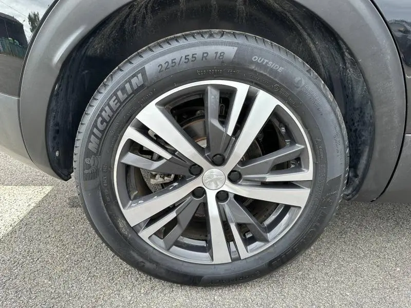Gros plan sur la jante alu bicolore et le pneu Michelin du côté gauche d’un Peugeot 3008 noir Perla Nera 2024 hybride rechargeable.