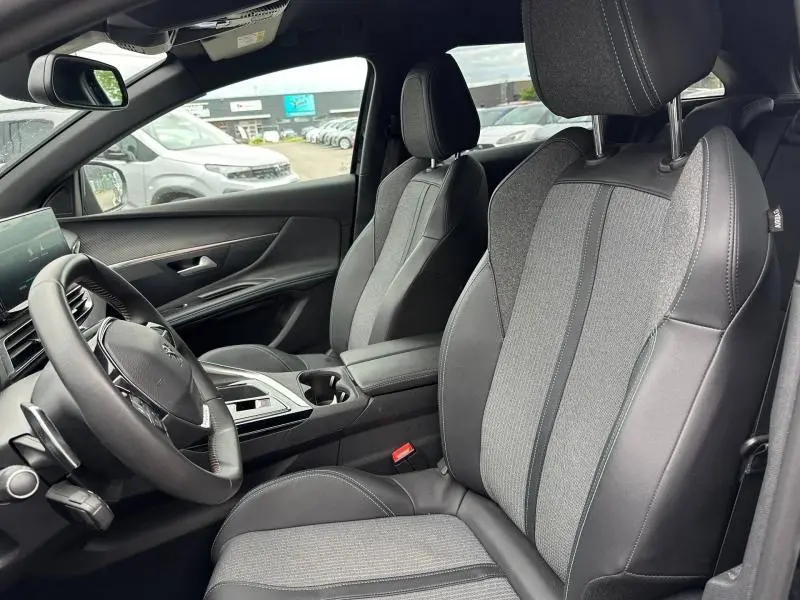 Intérieur avant du Peugeot 3008 Hybride 2024 vu côté gauche, sièges tissu et cuir noir avec console centrale.