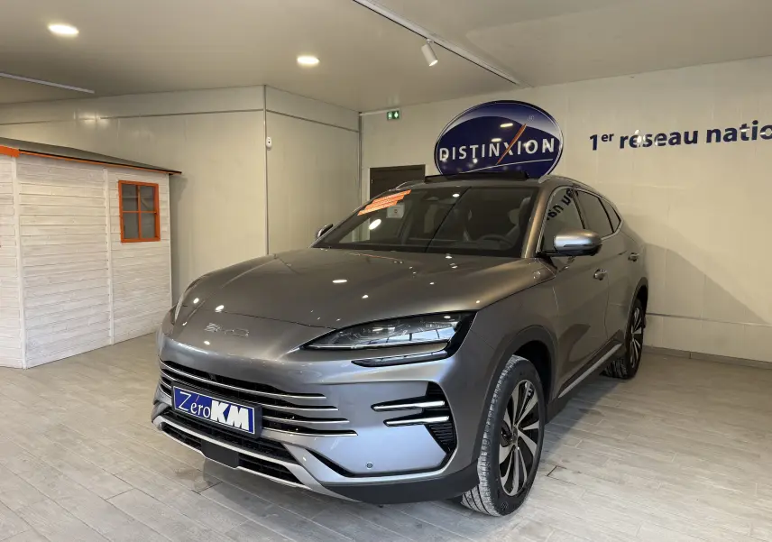 Vue 3/4 avant droite d'un BYD SEAL U hybride rechargeable gris métallisé exposé en showroom avec jantes bicolores et calandre horizontale.