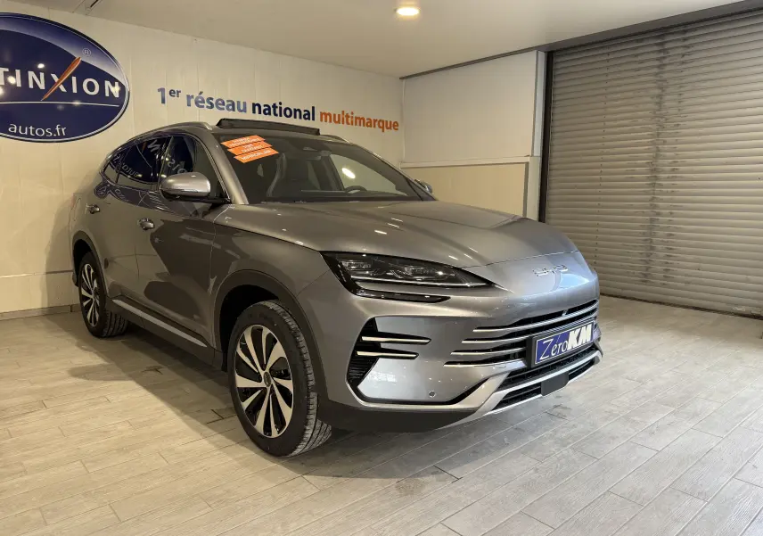 Vue 3/4 avant d'un BYD SEAL U hybride rechargeable gris métallisé avec jantes bicolores et calandre épurée en intérieur showroom.