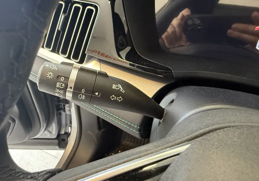 Gros plan sur la manette de clignotants côté gauche du tableau de bord intérieur du BYD SEAL U, cuir noir et surpiqûres vertes.