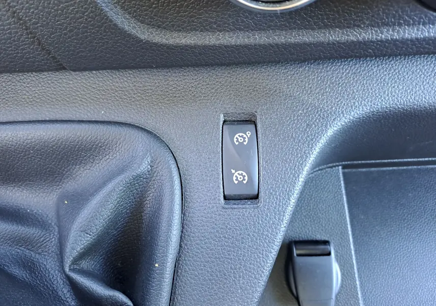 Gros plan sur l'interrupteur de régulateur de vitesse dans l'habitacle noir du Nissan Interstar blanc 2024.