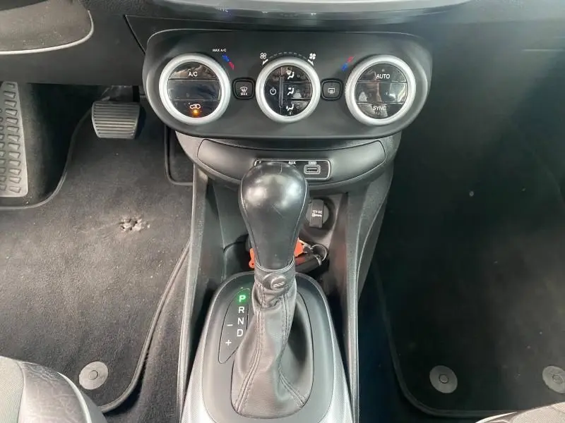 Gros plan sur la console centrale de la Fiat 500X noire, montrant la commande de boîte automatique et les réglages de climatisation.