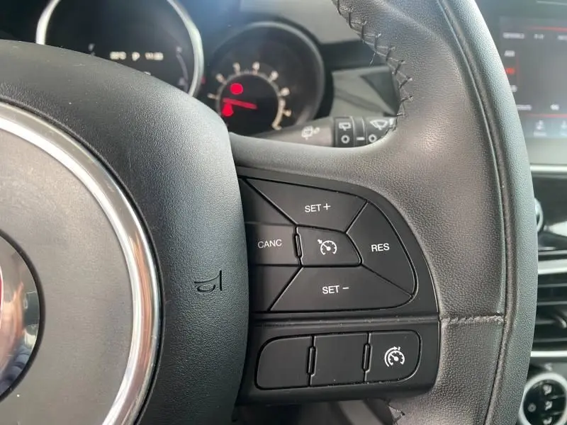 Gros plan sur les commandes du régulateur de vitesse au volant cuir noir d'une Fiat 500X 2018.