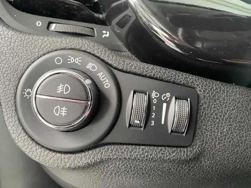 Gros plan sur les commandes d'éclairage et réglages du tableau de bord d'une FIAT 500X noire de 2018.