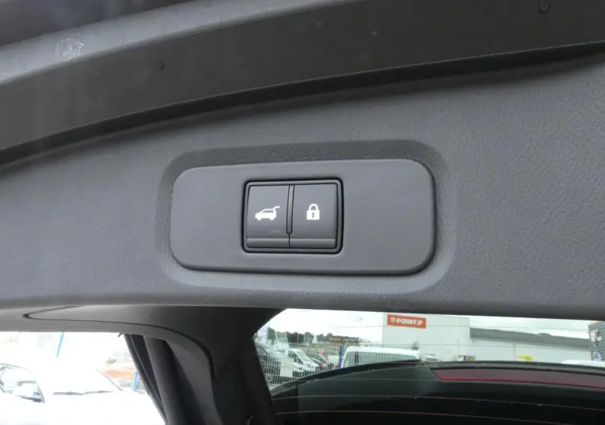 Boutons de hayon électrique et verrouillage intégrés sur le coffre d'un Nissan Qashqai gris métallisé, vue intérieure arrière.