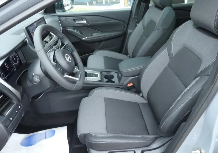 Vue intérieure côté conducteur du Nissan Qashqai 1.5 e-Power 2025, sièges gris bi-ton et volant cuir.
