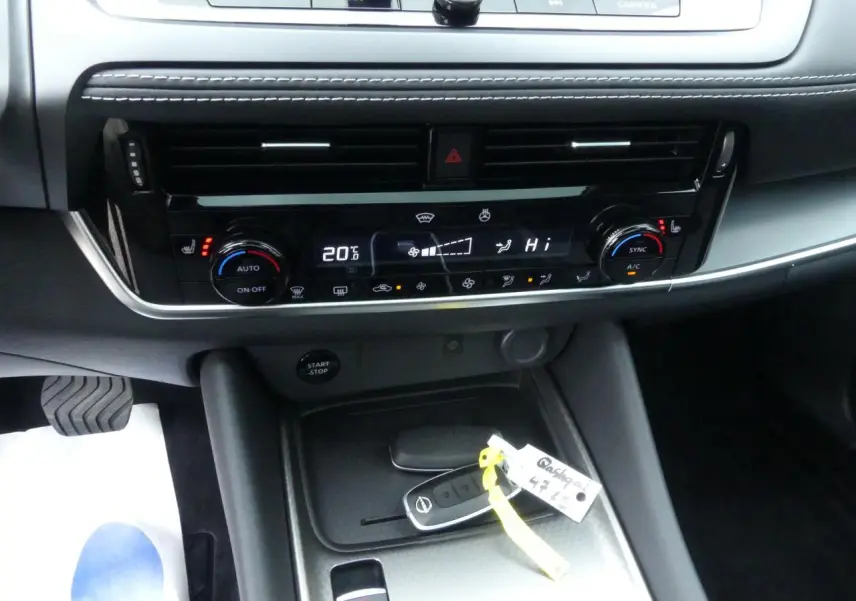 Détail de la console centrale du Nissan Qashqai 1.5 e-Power 2025 avec commandes climatisation et clé intelligente posée.