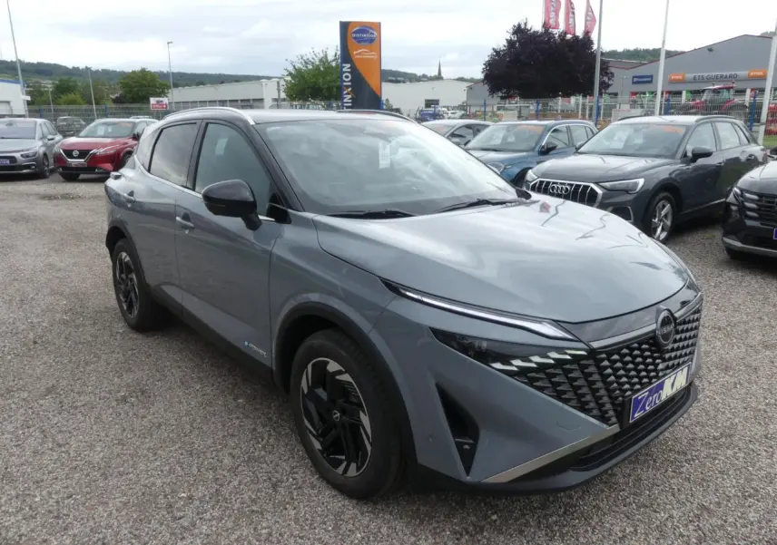 Nissan Qashqai 1.5 e-Power gris métallisé en 3/4 avant droit avec calandre distinctive et jantes noires.